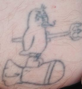 A penguin smoking a cigarette and wearing combat boots on a bomb, while holding a pitchfork tattoo