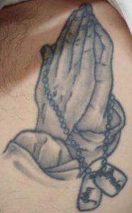 Praying hands with dog tags tattoo
